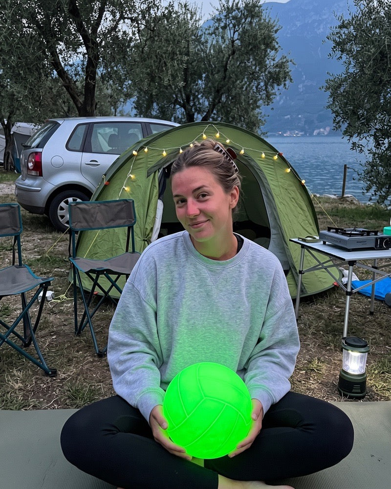 Kundenfoto: junge Frau mit leuchtendem Volleyball vor ihrem Zelt am Gardasee